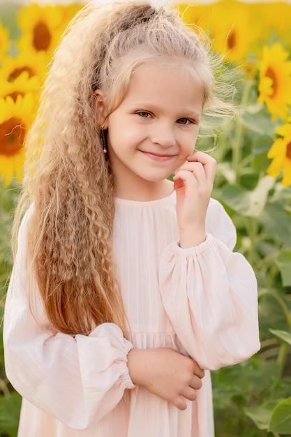 a blonde girl with long hair in a linen dress stands in a blooming field with sunflowers