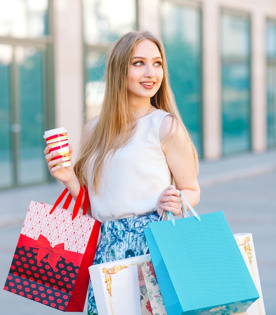 blonde girl, with shopping bags walking out from shop.