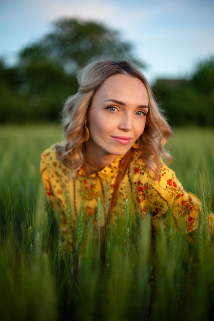 Blonde girl in a yellow retro style dress in a green field