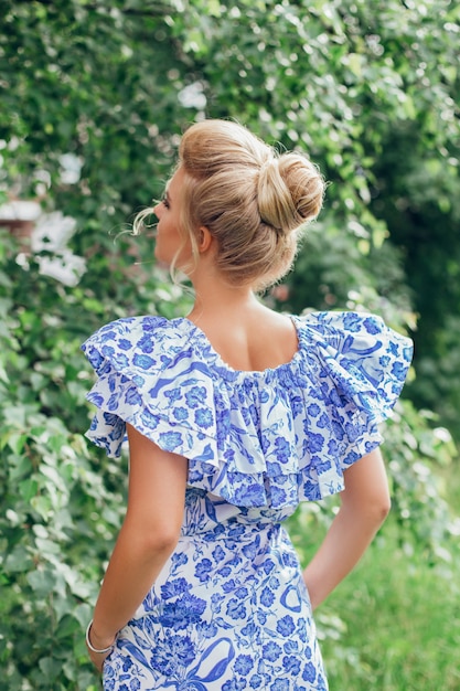 Blonde hair woman back with fashion hairstyle on summer garden background