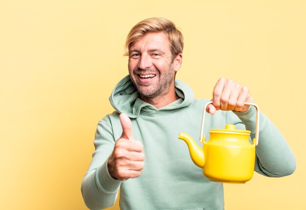 Photo blonde handsome adult man holding a teapot