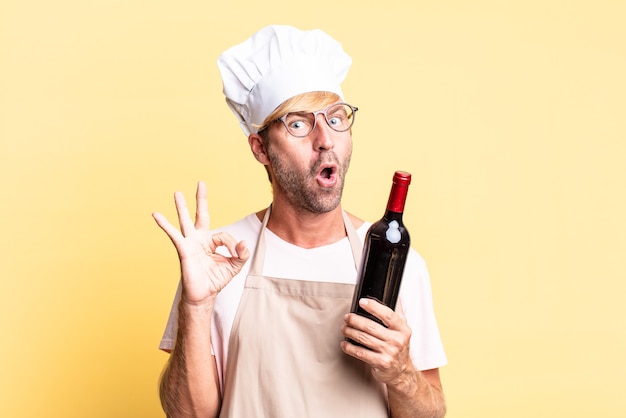 Blonde handsome chef  adult man holding a bottle of wine