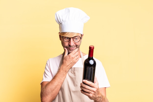 Photo blonde handsome chef  adult man holding a bottle of wine