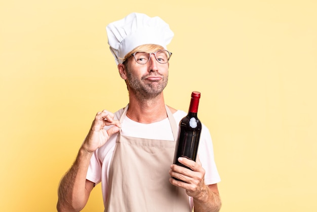 Blonde handsome chef  adult man holding a bottle of wine