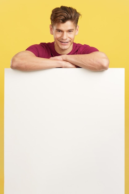 Blonde handsome man leaning on a blank panel