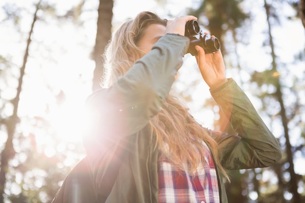 Blonde hiker looking through binoculars