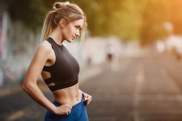 Blonde is engaged in fitness on the street Caucasian girl on the evening jog