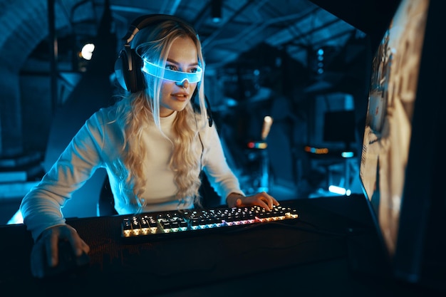 The blonde is playing a computer game Blogger in neon futuristic glasses