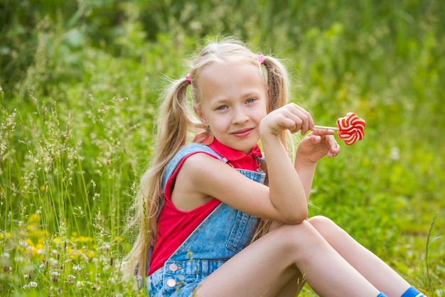 Blonde little girl with long hair and candy on a stick