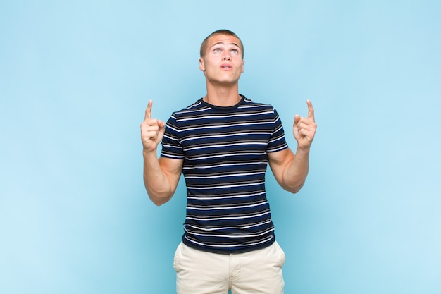 Blonde  man feeling awed and open mouthed pointing upwards with a shocked and surprised look