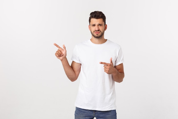 Blonde man over isolated yellow wall frightened and pointing to the side.