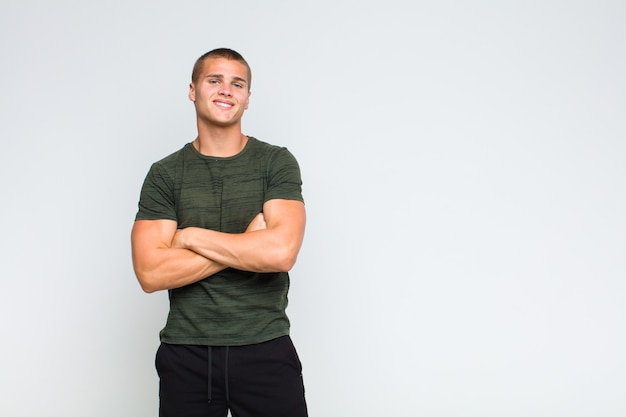 Blonde man looking like a happy, proud and satisfied achiever smiling with arms crossed