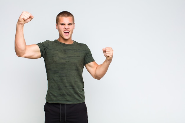 Blonde  man shouting triumphantly, looking like excited, happy and surprised winner, celebrating