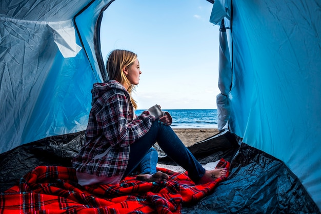 blonde nice young woman stay on the tent at the camping freedom alternative no rulez on the snd in front of the sea