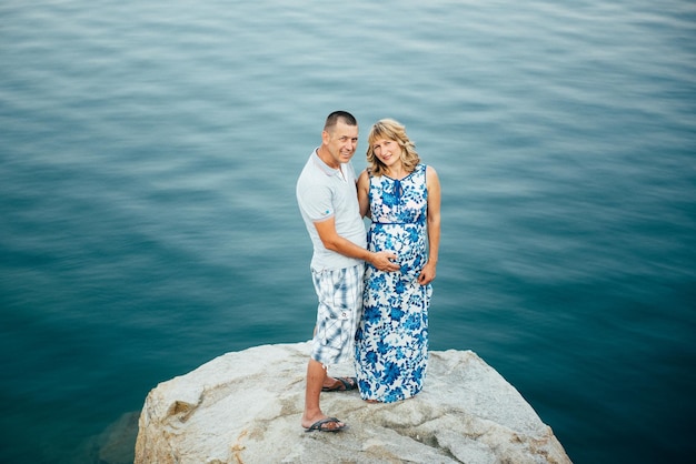 Blonde pregnant girl mom in a blue dress and a man