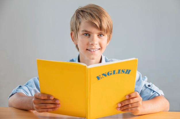 Blonde preteen schoolboy holding yellow english book