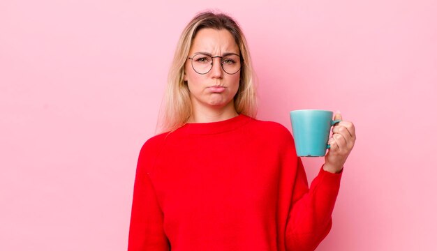 Blonde pretty woman feeling sad and whiney with an unhappy look and crying coffee cup concept