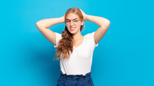 Blonde pretty woman feeling stressed worried anxious or scared with hands on head panicking at mistake