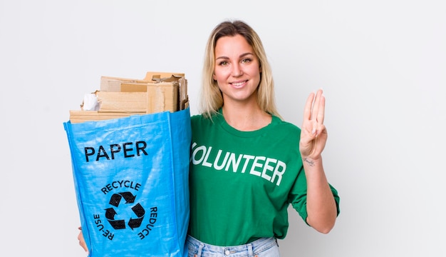 Blonde pretty woman smiling and looking friendly showing number three recycle concept