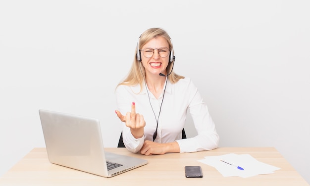 Blonde pretty woman young blonde woman feeling angry, annoyed, rebellious and aggressive and working with a laptop