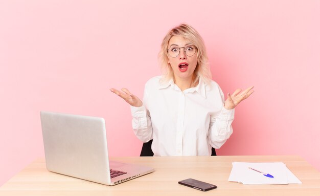 Blonde pretty woman young pretty woman feeling extremely shocked and surprised. workspace desk concept