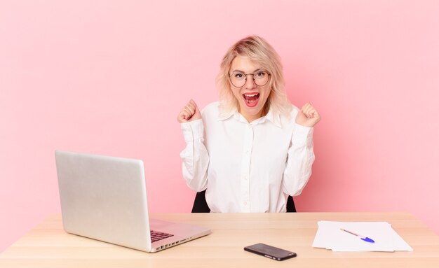 Blonde pretty woman young pretty woman feeling shocked,laughing and celebrating success. workspace desk concept