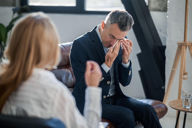 Blonde psychologist talking to a male patient at her office