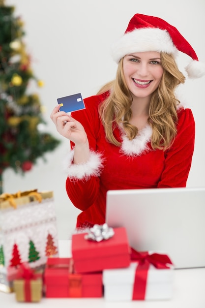 Blonde shopping online with laptop while smiling at camera