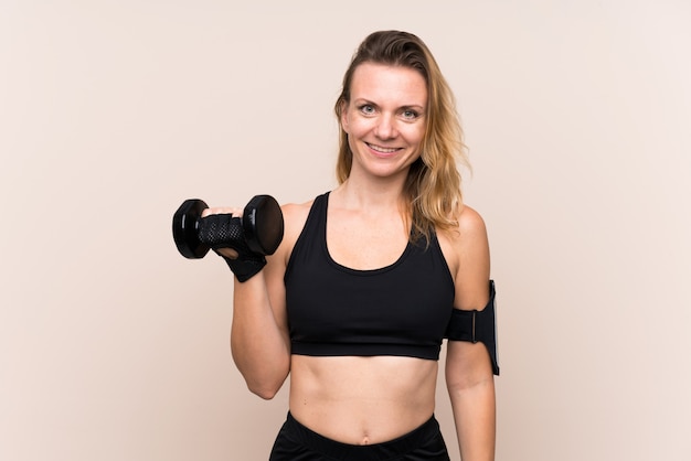 Blonde sport woman over isolated wall making weightlifting