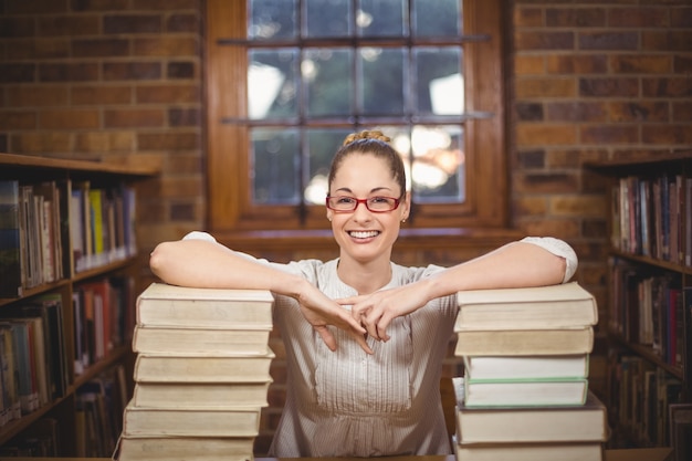 Photo blonde teacher standing between books in the library