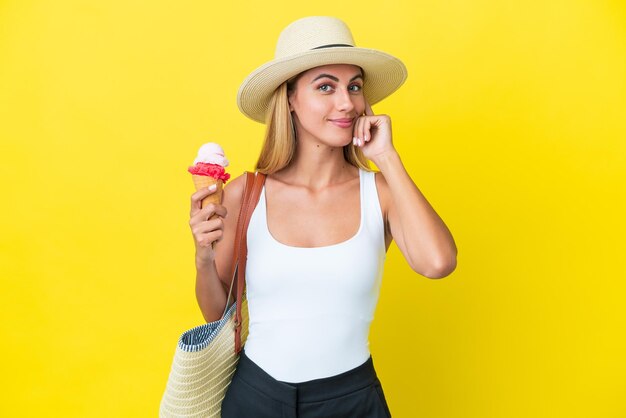 Blonde Uruguayan girl in summertime holding ice cream isolated on yellow background thinking an idea