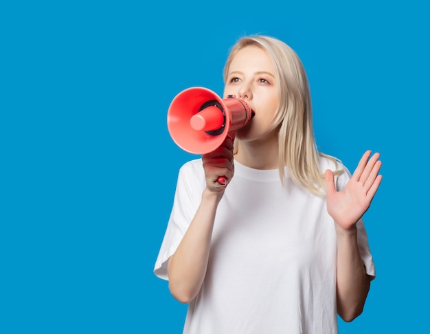 Blonde in white t-shirt with megaphone on blue space