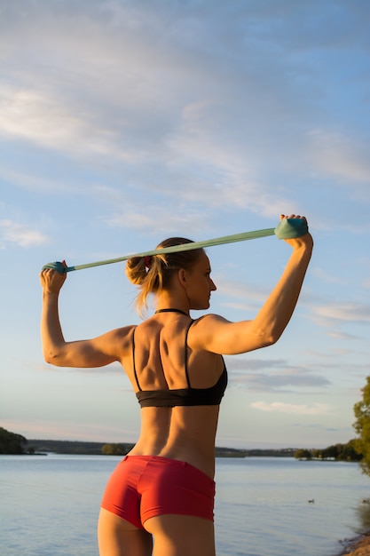 The blonde with a sporting figure does exercises in park