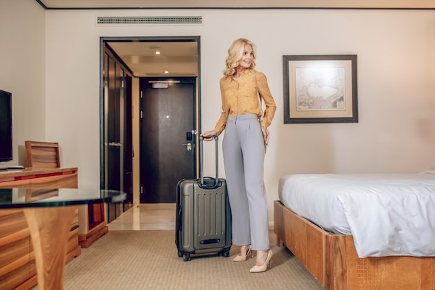 Blonde woman. Blonde elegant woman with a suitcase in a hotel room