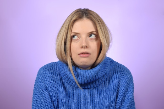 A blonde woman in a blue sweater looks up and looks up