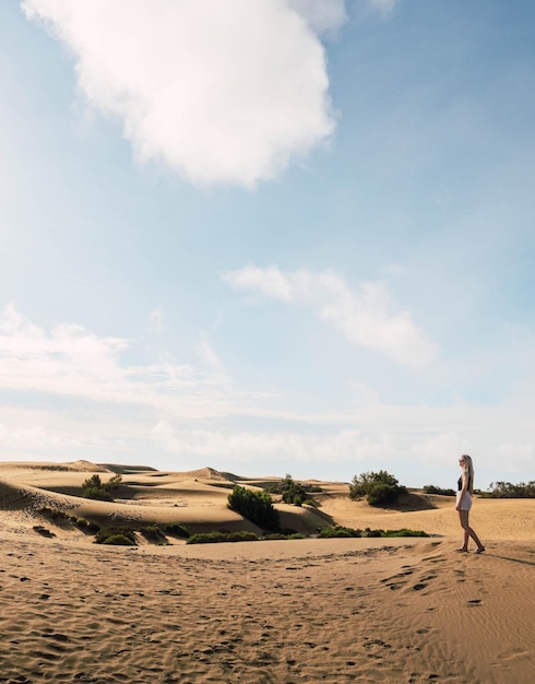 Blonde woman in the dunes desert in a sunny day