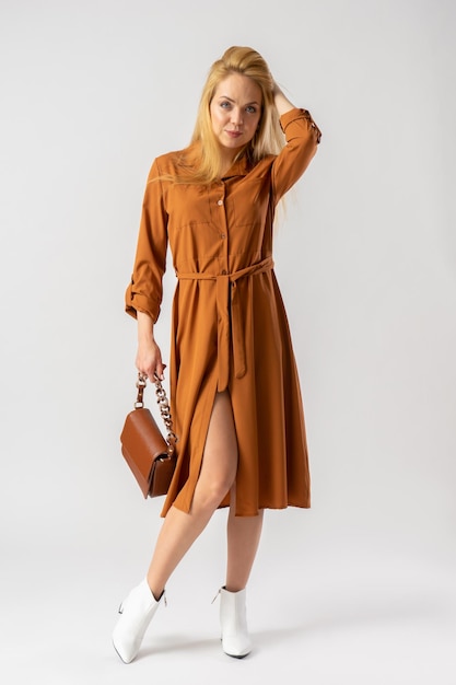 Blonde woman in an elegant casual brown dress with a women's handbag