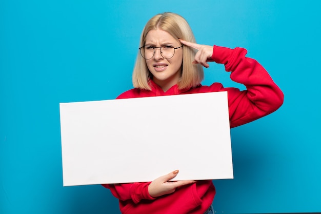 Blonde woman feeling confused and puzzled, showing you are insane, crazy or out of your mind