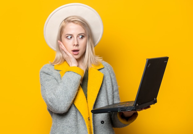 Photo blonde woman in hat and coat with laptop