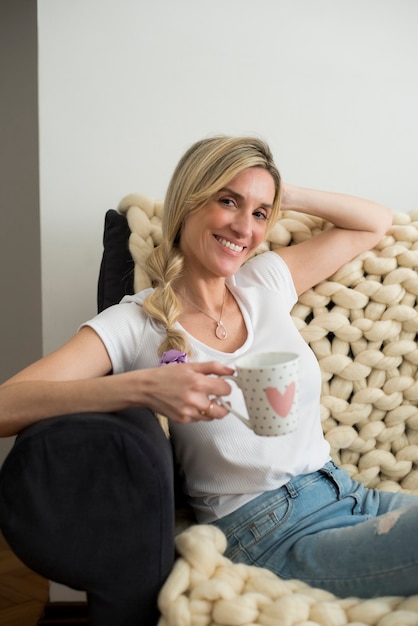 Blonde woman having tea on the sofa