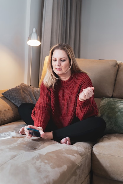 Blonde woman at home with smartphone