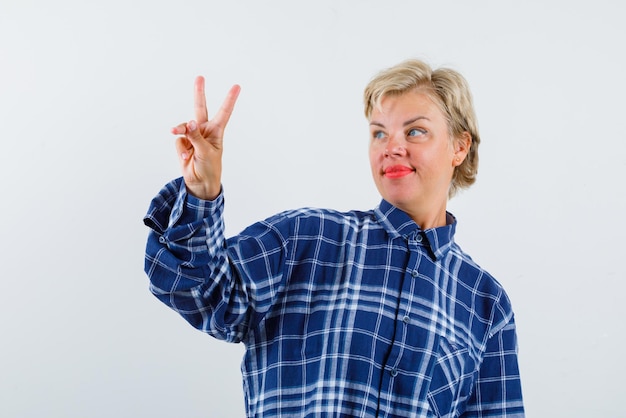 The blonde woman is showing a victory gesture with hand on white background