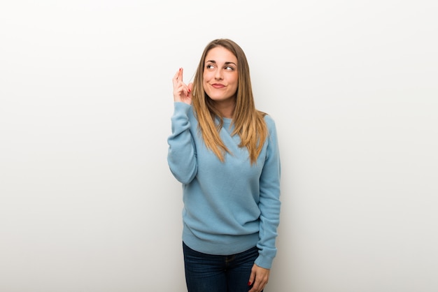 Blonde woman on isolated white background with fingers crossing and wishing the best