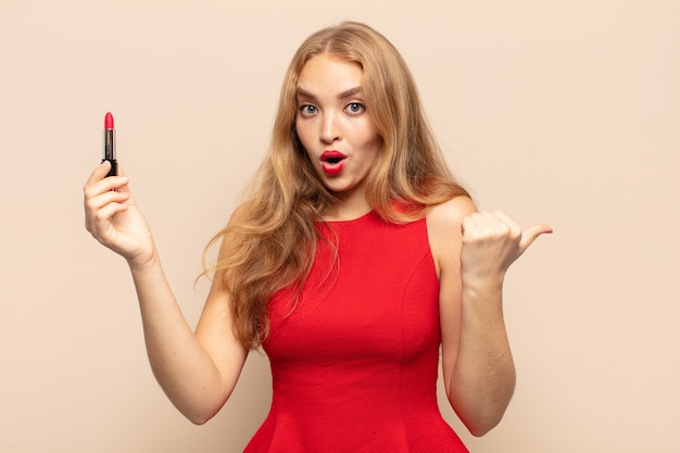 Blonde woman looking astonished in disbelief, pointing at object on the side and saying wow, unbelievable