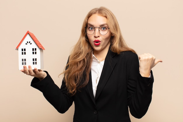 Blonde woman looking astonished in disbelief, pointing at object on the side and saying wow, unbelievable