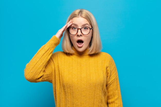 Blonde woman looking happy, astonished and surprised, smiling and realizing amazing and incredible good news