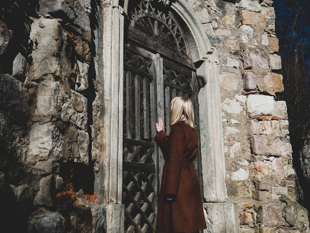 Photo blonde woman near ruins of old door in a castle