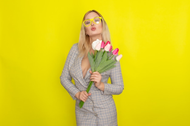 Blonde woman in plaid dress holding tulips bouquet