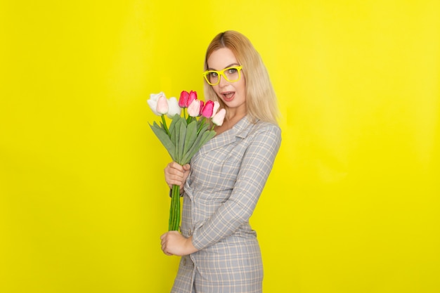 Blonde woman in plaid dress holding tulips bouquet