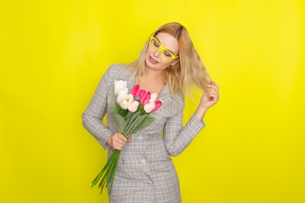 Blonde woman in plaid dress holding tulips bouquet